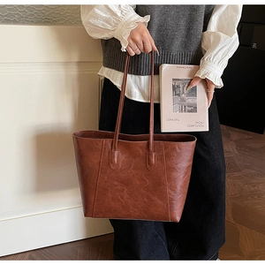 Detail of vintage brown PU leather tote bag showing fine cracked texture and minimalist design