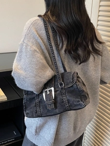 Sac bandoulière chic en denim gris foncé avec boucle argentée, porté par un mannequin