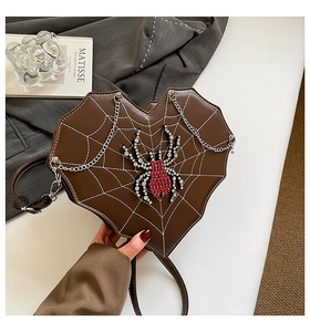 Detail der herzförmigen braunen Tasche mit weißem Spinnennetz und Strass-Spinne