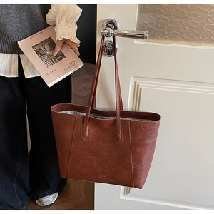 Close-up of the vintage brown PU leather tote bag hanging on a white door handle