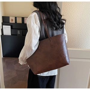 Detailed close-up of brown PU leather tote bag with vintage texture on a shoulder strap
