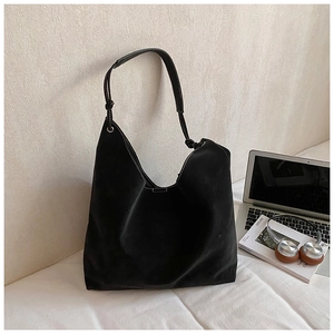 Detail of black tote bag showing white contrast stitching and knotted strap design