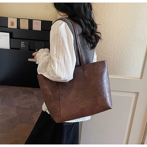 Close-up of dark brown vintage oil wax leather tote bag worn as a shoulder bag