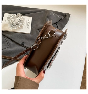 Detail der braunen Herz-Tasche mit Silberketten, Badges und weißen Kontrastnähten