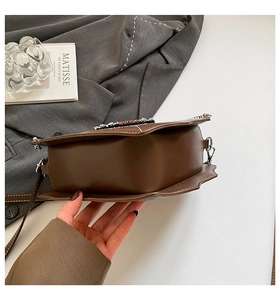 Detail der herzförmigen dunkelbraunen Ledertasche mit Wellenrand und Diamant-Logo-Verzierung