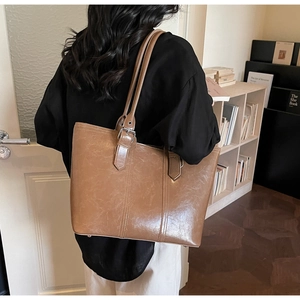 Détail d'un sac cabas en cuir marron avec boucles en métal argenté de dos sur mannequin