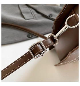 Detail der Herztasche mit weißen Nähten, Metallschnallen und brauner Ledertextur