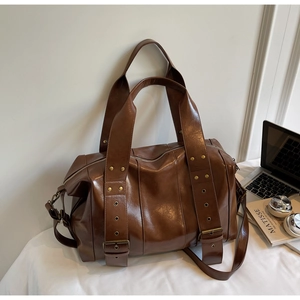 Dettaglio macro della borsa tote retrò marrone scuro con rivetti dorati e trama in pelle cerata