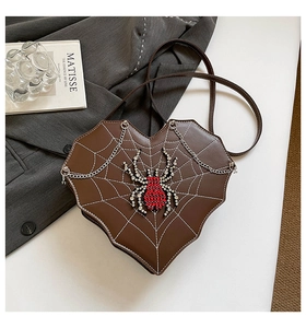 Nahaufnahme der herzförmigen Handtasche mit Spinnennetz-Druck und Strass-Spinnen-Anhänger