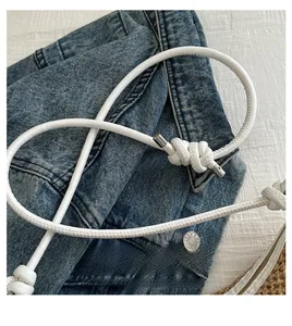 Détail de la poignée en cuir tressé blanc avec nœud décoratif sur un sac de plage