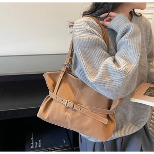 Détail du sac cabas vintage en cuir marron avec ceinture décorative et boucle argentée