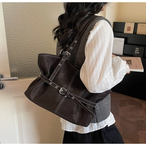 Détail du sac cabas en cuir marron foncé avec coutures contrastées et brides à boucle