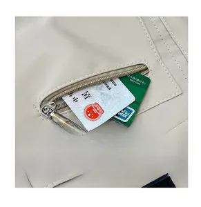 Détail de la poche zippée avant du sac fourre-tout en nylon beige avec rangement