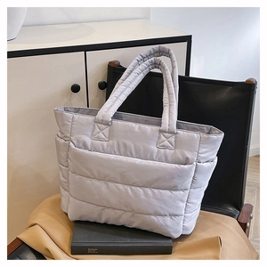Detailed view of grey quilted nylon tote bag with horizontal stitching on a black chair