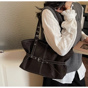 Détail du sac cabas en cuir marron foncé avec coutures blanches et boucle de ceinture