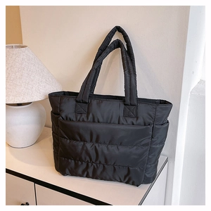 Detail of black quilted tote bag with padded nylon texture and convenient side pocket