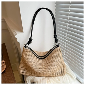 Détail du sac de plage en paille tressée avec bandoulières noires et fermeture éclair en métal