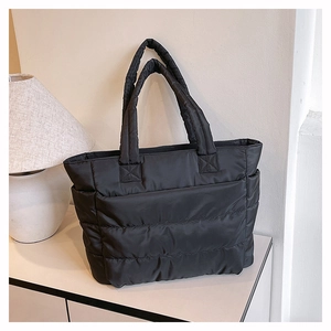 Detail of black quilted puffer tote bag showing the plush texture and side pocket