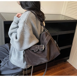 Détail d'un sac cabas en cuir marron foncé avec coutures blanches contrastées et boucle