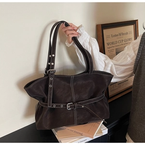 Détail d'un sac cabas en cuir marron avec surpiqûres blanches et boucle argentée réglable