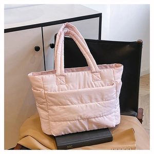 Detail of light pink quilted tote bag with padded handles on a chair in a minimalist room