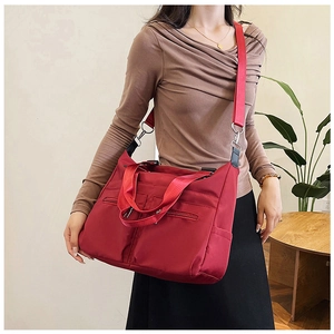 Détail d'un grand sac cabas en nylon rouge avec fermetures éclair et bandoulière