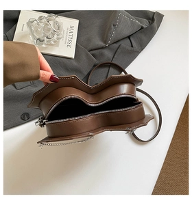 Detail einer braunen sternförmigen Ledertasche mit weißen Kontrastnähten und Silberzipper