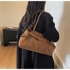 Detalle de bolso tote de ante marrón con correa de hombro y hebilla plateada elegante