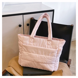 Detail of pink quilted nylon tote bag placed on a modern black chair for commute