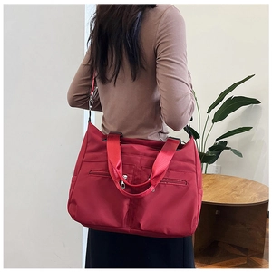 Vue détaillée d'un grand sac cabas rouge en nylon imperméable porté par un mannequin
