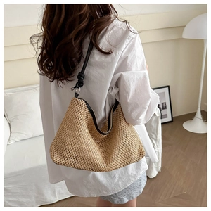 Détail du sac bandoulière en paille tressée avec bordure en cuir noir et nœud décoratif
