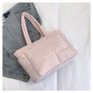 Detail of light pink quilted nylon tote bag featuring soft padded texture and top handles