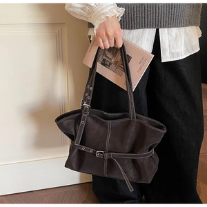 Détail d'un grand sac cabas en cuir marron avec surpiqûres contrastées et boucle métallique