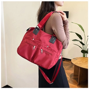 Sac cabas rouge en nylon imperméable avec poches zippées et lanières en cuir sur mannequin