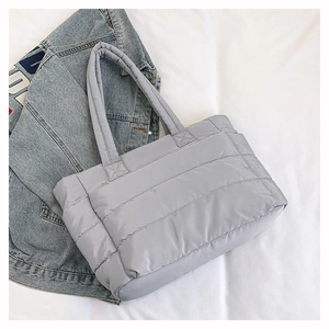 Detail of light gray quilted nylon tote bag with wide padded handles and soft texture