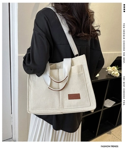 Detail of off-white corduroy tote bag featuring brown leather logo and adjustable strap