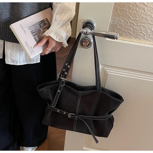 Détails d'un sac cabas marron foncé avec surpiqûres blanches contrastées sur porte en bois