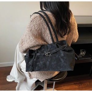 Detalle de bolso tote negro mate con hebilla metálica sobre el hombro del modelo