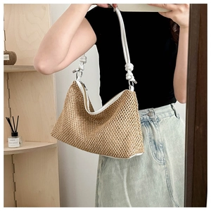 Selfie miroir montrant un sac bandoulière en paille tissée avec détails de nœuds blancs