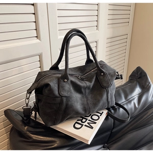 Detail of charcoal gray matte Boston bag with handles and strap on Tom Ford book