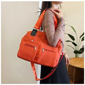 Détail du sac en nylon orange imperméable montrant les poches avant et la bandoulière