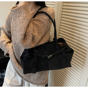 Detalle de bolso tote de ante negro con correa de cuero ajustable y hebilla dorada