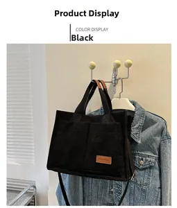 Detail of black corduroy tote bag showing front pockets and brown fashion leather label