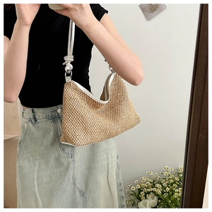 Détail du sac à bandoulière en paille tissée à la main avec fines lanières en cuir blanc