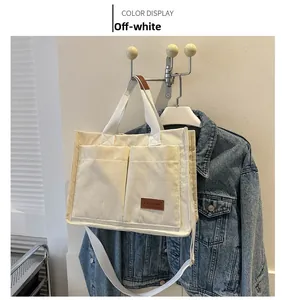 Detail of beige corduroy tote bag showing front pockets and brown leather brand label