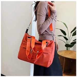 Détail du sac à main en nylon orange imperméable montrant l'épaisseur et la bandoulière réglable