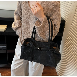 Detalle de un bolso tote grande de ante negro con correas finas y hebilla decorativa