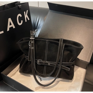 Détail d'un sac cabas noir minimaliste avec surpiqûres blanches dans son coffret cadeau