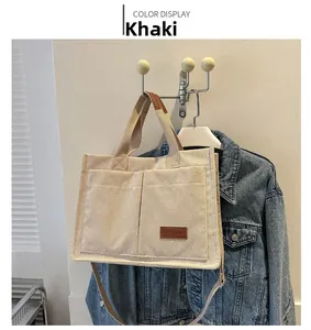 Detail of khaki corduroy tote bag showing front pockets and brown leather brand label