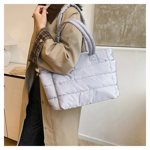 Detailed view of lilac quilted nylon tote bag worn by model in minimalist indoor setting